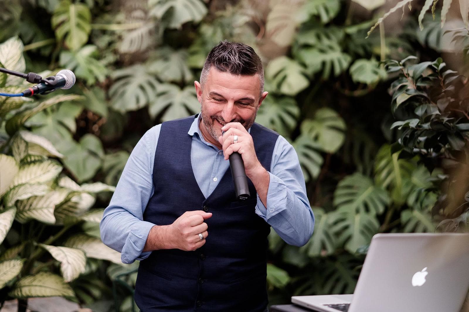 Antonio Riccio singing into a microphone in front of a laptop and mixer
